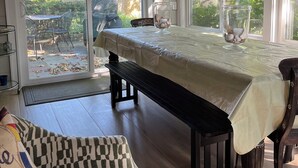 A dining area with a table covered by a white tablecloth, a bench, and a chair. There is a glass vase with flowers on the table. - Relax and enjoy this private location in Hampton Bays (Hampton Bays)