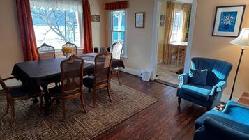 A dining area with a table and chairs, a blue armchair, and a rug.