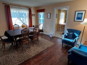 A dining area with a table and chairs, a blue armchair, and a rug.