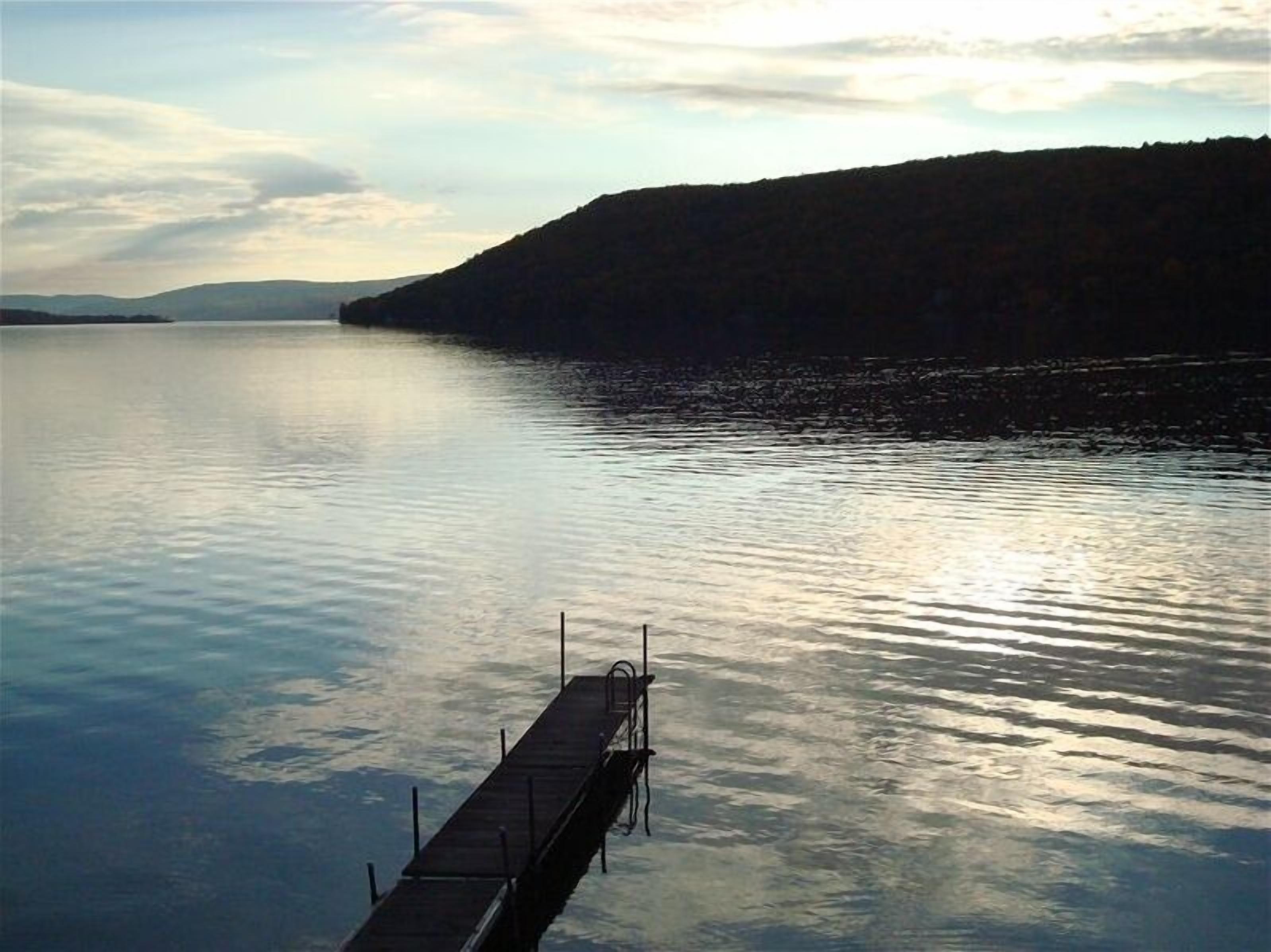 Un lac paisible avec une jetée en bois qui s’avance sur l’eau.