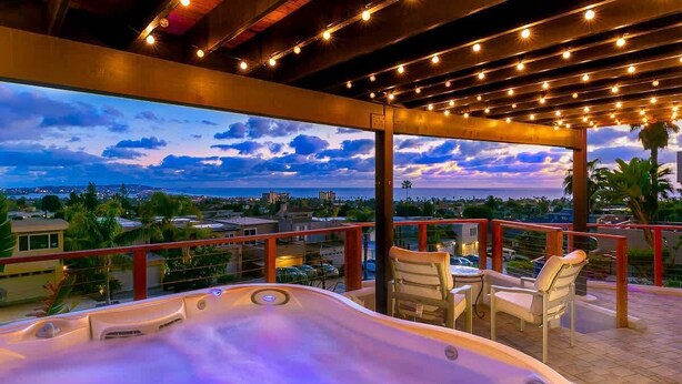 A hot tub with a view of the city at dusk.
