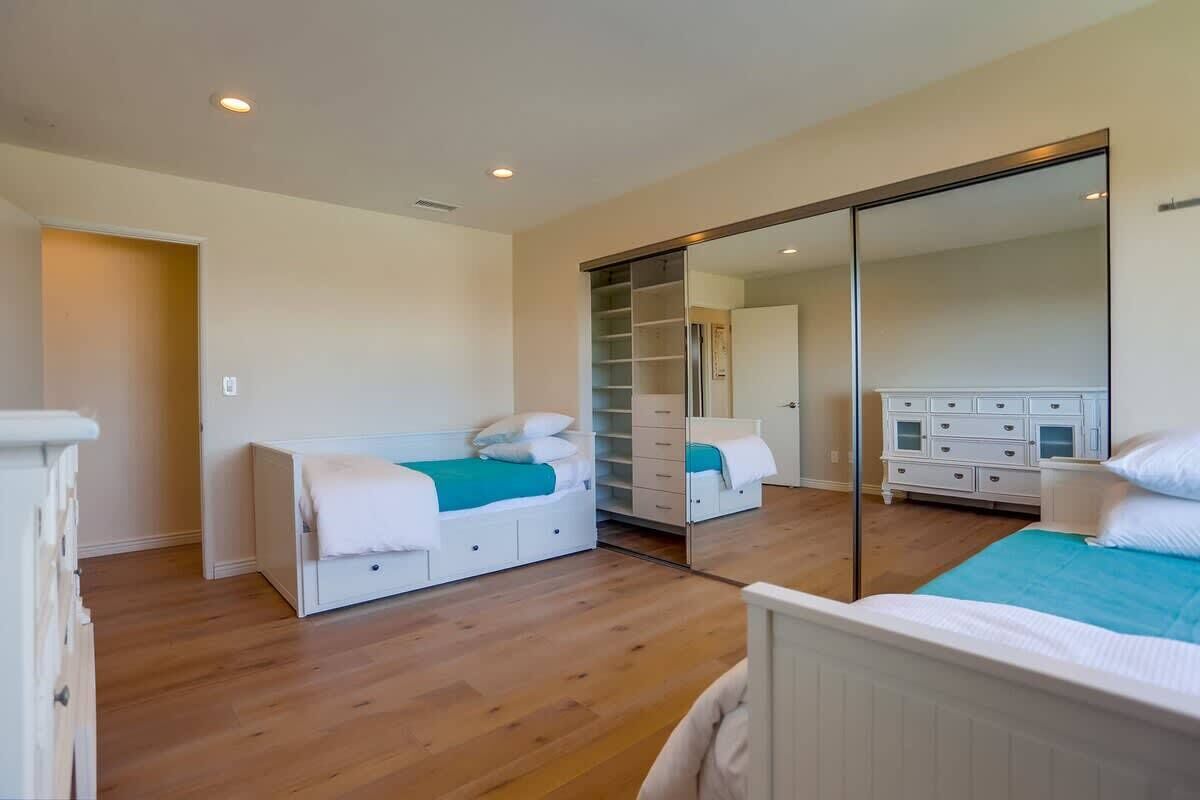Une chambre à coucher comprenant un lit, une armoire, une commode et une porte de placard avec un miroir.