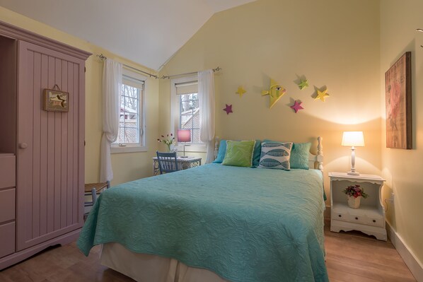 A bedroom with a bed, nightstand, dresser, and window with curtains.