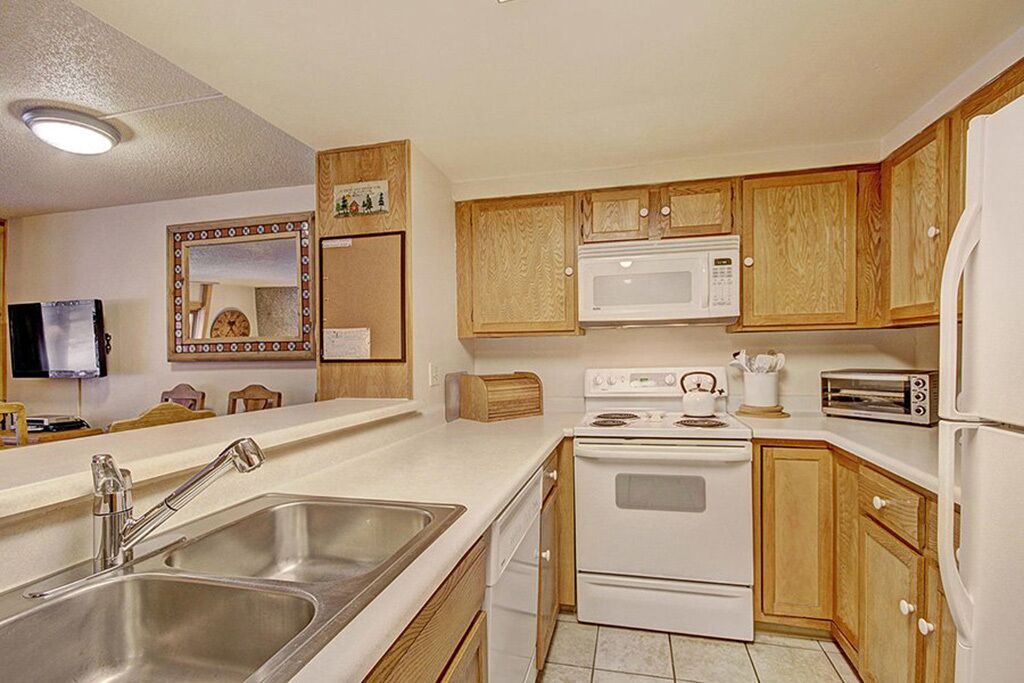 A kitchen with wooden cabinets, a microwave, a stove, a sink, and a toaster.