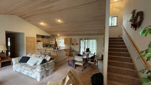 Een ruime woonkamer met houten plafond, een keuken met houten kastjes, een eethoek en een trap.
