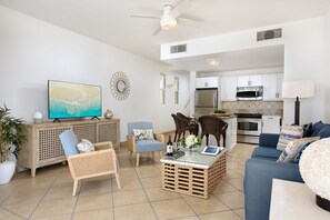 A modern living room with a television, seating area, and kitchen.