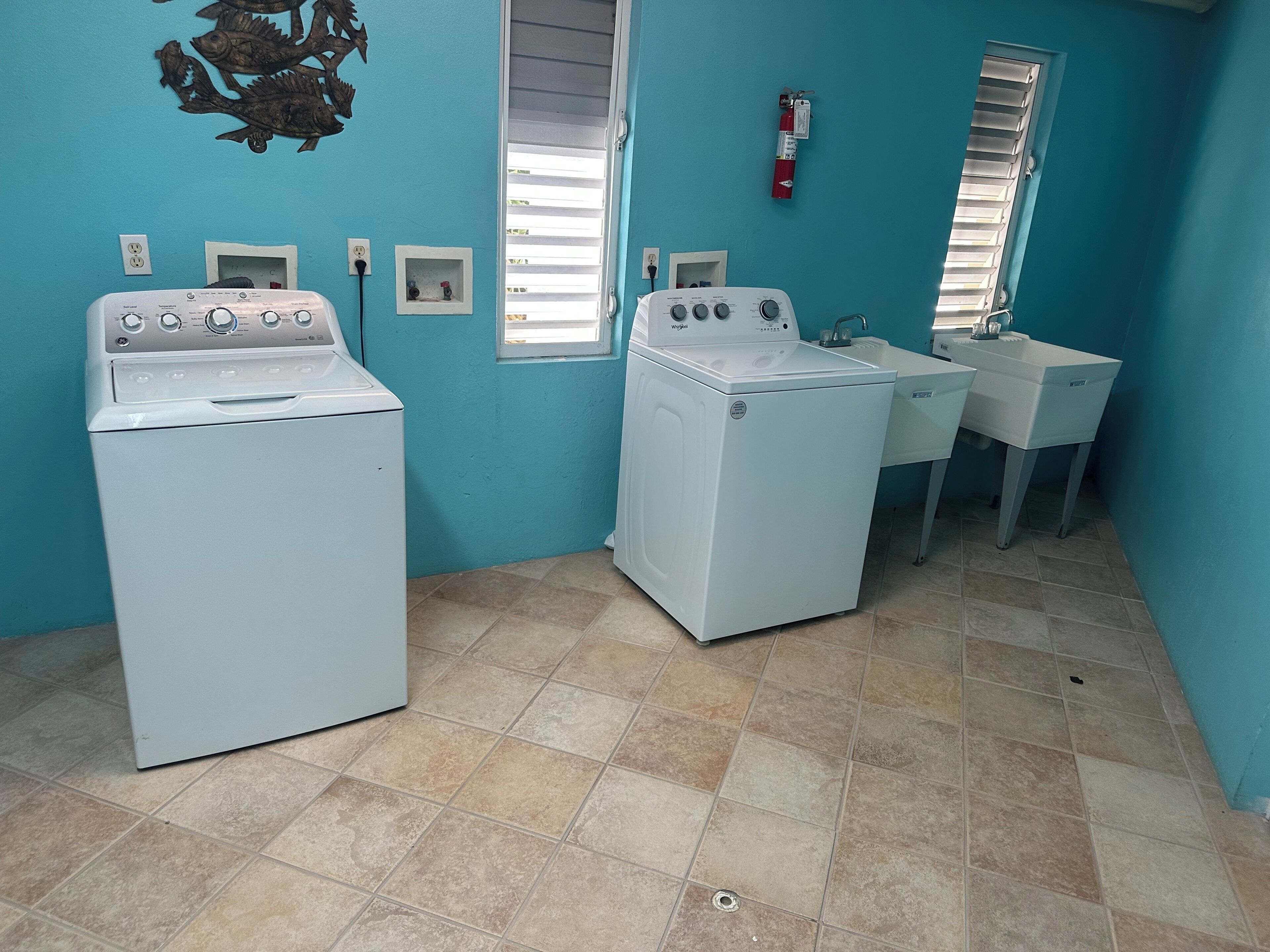 A laundry room with two washing machines, a sink, and a fire extinguisher.