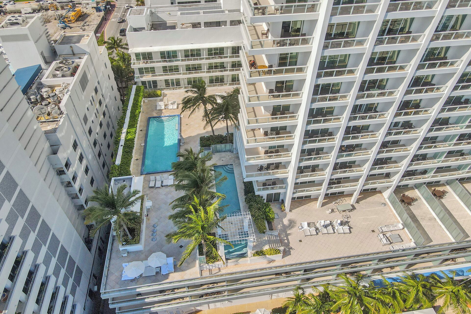 Un hôtel de grande hauteur doté de nombreux balcons, d’une piscine sur le toit et d’un espace piscine aménagé avec des palmiers.