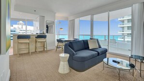 A modern hotel room with a balcony, a sofa, a dining area, and a view of the ocean. - Ocean view corner suite. full kitchen, washer & dryer, 2 full bathrooms (Miami Beach)