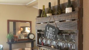 Ein Weinkühlschrank mit Flaschen und Gläsern, eine Uhr und ein Schild mit der Aufschrift 'Wine time!'