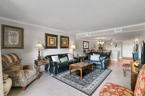 A living room with a sofa, armchair, coffee table, and a dining area with chairs and a table. - Stunning Condo in Plantation Club with Views of the Golf Course and On-site Amenities! (Hilton Head)