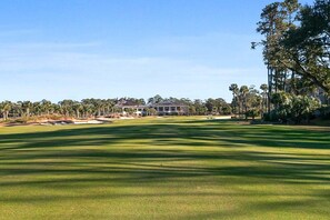 A golf course with a clubhouse in the background. - Stunning Condo in Plantation Club with Views of the Golf Course and On-site Amenities! (Hilton Head)