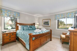 A bedroom with a wooden bed, a nightstand, a lamp, a chair, and a desk. - Stunning Condo in Plantation Club with Views of the Golf Course and On-site Amenities! (Hilton Head)