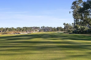 Un campo de golf con un club de campo al fondo.