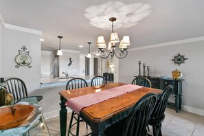 A dining area with a wooden table, black chairs, a chandelier, and wall decor. - Stunning Condo in Plantation Club with Views of the Golf Course and On-site Amenities! (Hilton Head)
