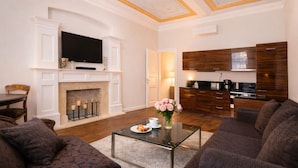 A living room with a fireplace, a television, a dining area, and a kitchen with wooden cabinets.