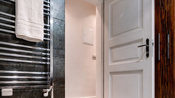A hallway with a glass floor, a white door, and a towel hanging on a metal rack.