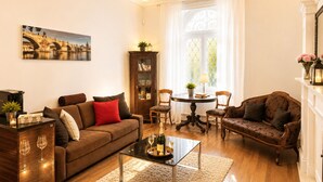 A living room with a sofa, armchairs, a coffee table, a cabinet, and a painting on the wall.