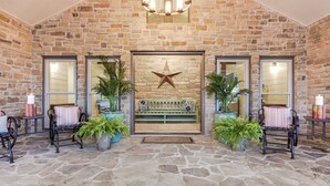 Un vestíbulo con paredes de piedra, una decoración con estrella, un banco y plantas en macetas.