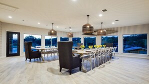 Un comedor amplio con una mesa larga, varias sillas e iluminación colgante.