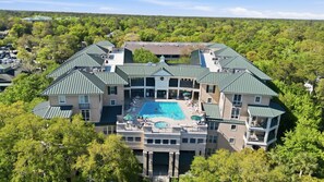 A large resort with multiple buildings, a central swimming pool, and surrounding lush greenery. - Beautiful 2nd Floor Villa Near Coligny Plaza (Hilton Head Island)