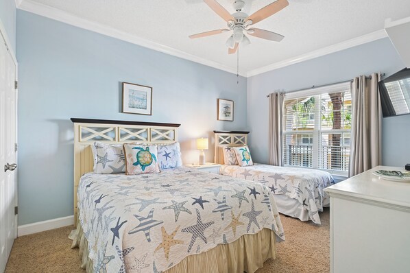A bedroom with a bed, a ceiling fan, a window with blinds, and a door.