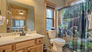 Un baño con armarios de madera, un espejo grande, un lavamanos y un inodoro.