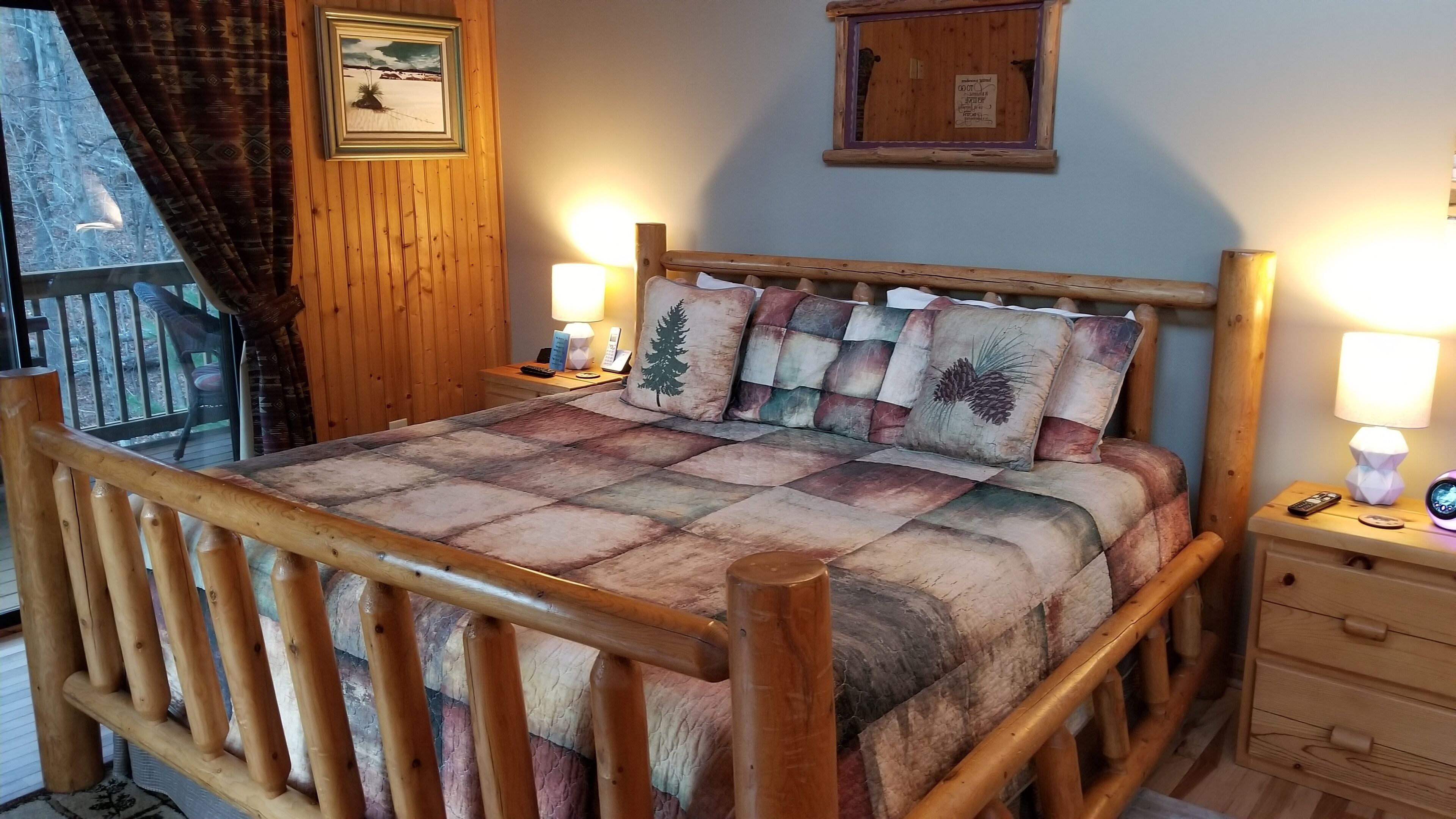 Un lit en bois avec une couvre-lit matelassé, une table de chevet avec une lampe et une fenêtre avec des rideaux.