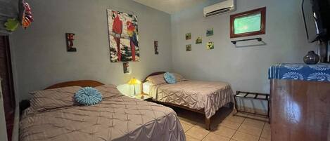A room with two beds, a ceiling fan, an air conditioner, a TV, and a window with a view.