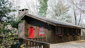A rustic cabin with a wooden exterior, a red door, and a small porch. - The Dala House | Scandinavian Retreat in Blowing Rock (Blowing Rock)