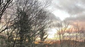 A wooden bridge in a forested area with bare trees and a sunset in the background. - The Dala House | Scandinavian Retreat in Blowing Rock (Blowing Rock)