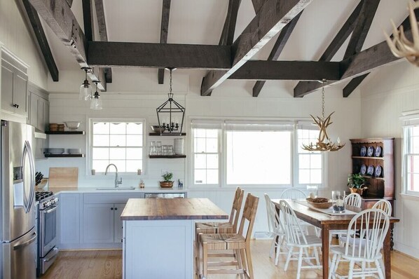 A spacious kitchen with a central island, wooden chairs, and a dining table. - The Dala House | Scandinavian Retreat in Blowing Rock (Blowing Rock)