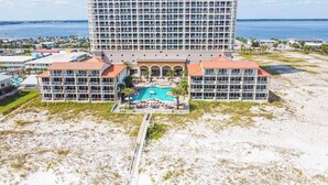 A hotel with a central pool, multiple balconies, and a view of the ocean. - Beach Club 1406 - 𝑺𝒆𝒂𝒔𝒊𝒅𝒆 𝑺𝒆𝒓𝒆𝒏𝒊𝒕𝒚 (Pensacola Beach)