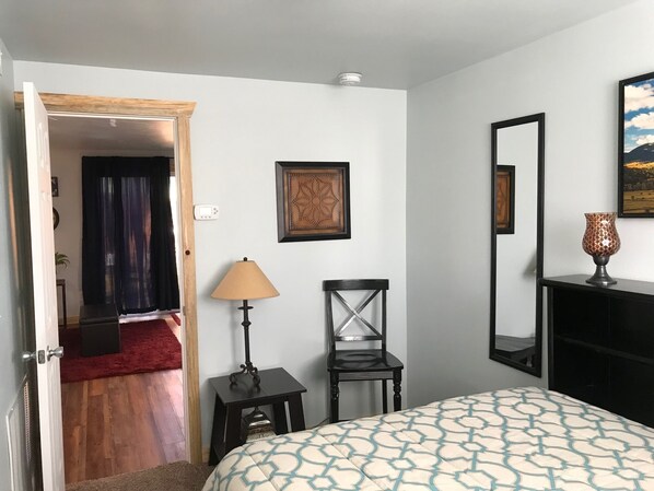 Une chambre à coucher comprenant un lit, une chaise, une lampe, une cheminée et une porte donnant sur une autre pièce.
