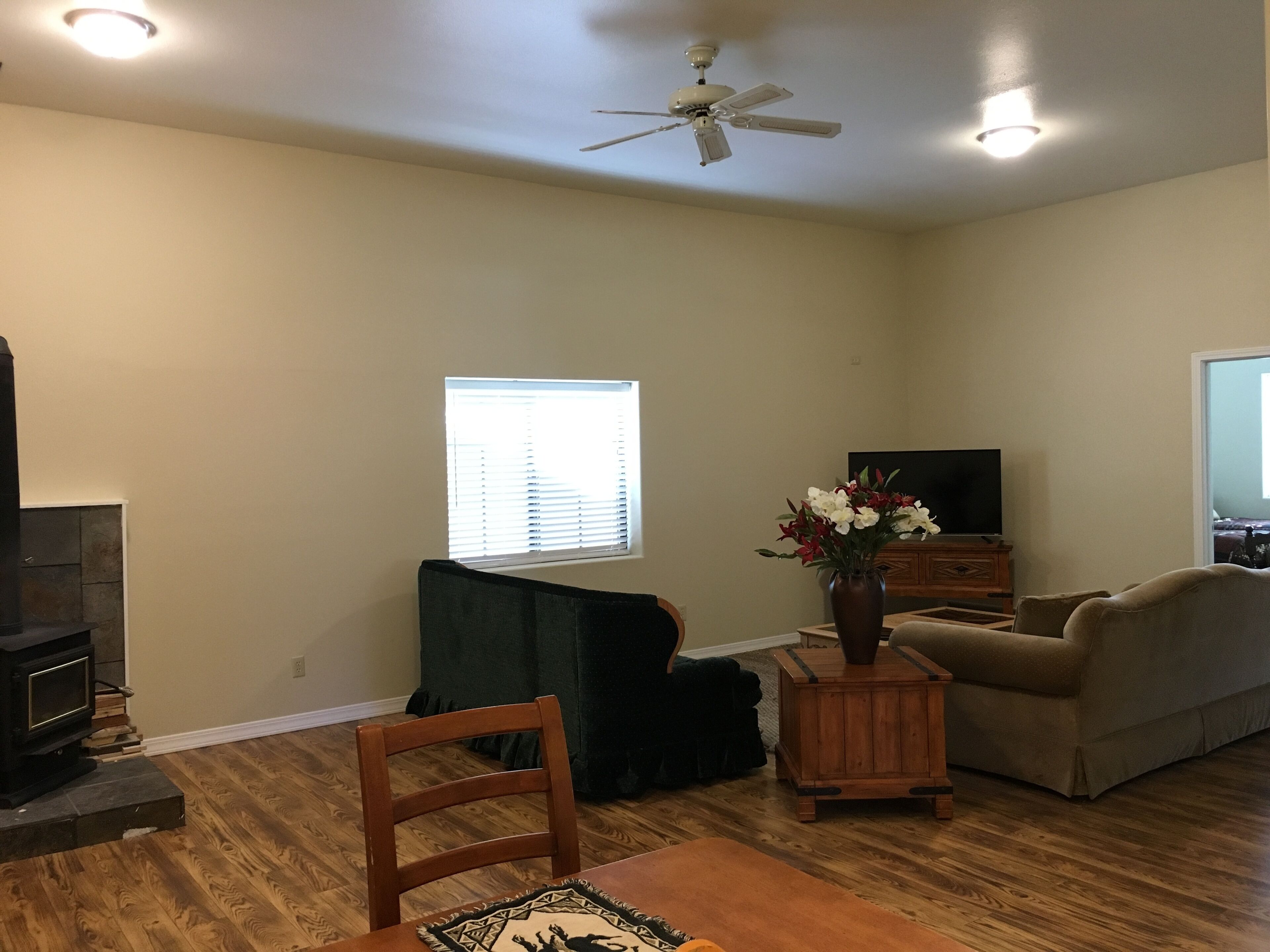A living room with a fireplace, a television, a sofa, a coffee table, and a ceiling fan.