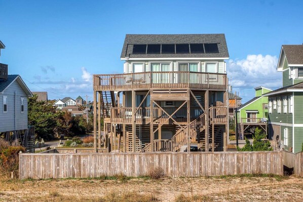 A two-story house with a wooden deck and a balcony. - Oceanfront Dog Friendly Home in Waves w/ Private Pool, Hot Tub, Tiki Bar, Grill (Waves)