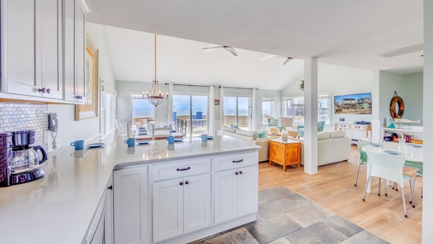 A spacious kitchen with a large island, white cabinetry, and a view of the ocean. - Oceanfront Dog Friendly Home in Waves w/ Private Pool, Hot Tub, Tiki Bar, Grill (Waves)