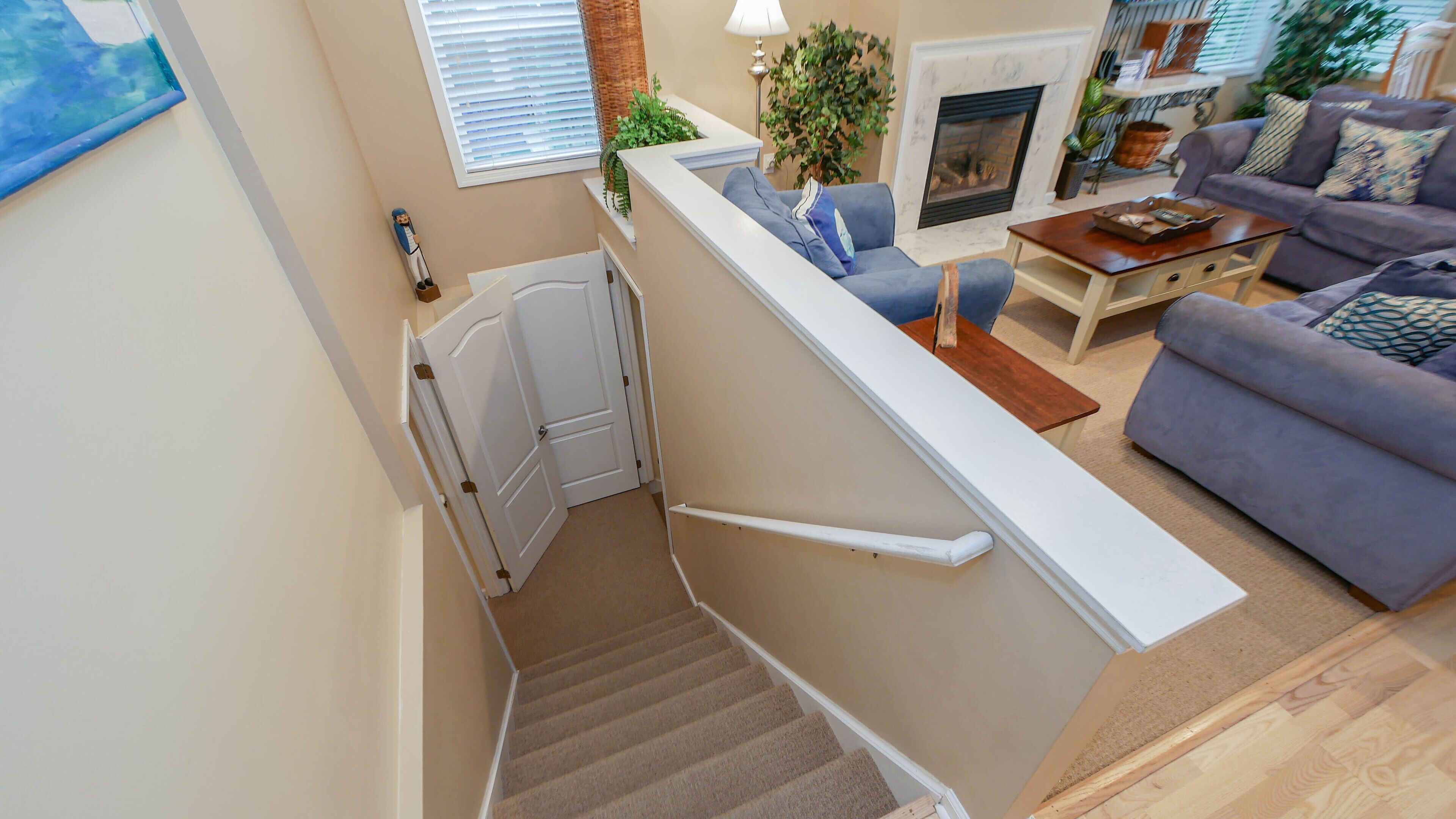 Un escalier menant à un espace de vie comprenant une cheminée, un canapé et une table basse.
