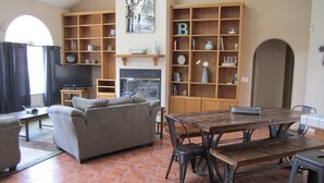 Un salon comprenant un canapé, un téléviseur, une cheminée et une table à manger avec des chaises.