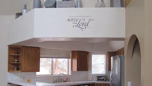 Une cuisine moderne dotée d’un îlot central, de meubles en bois, d’un réfrigérateur en acier inoxydable et d’un escalier en bois.
