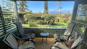 A sunlit patio with two chairs and a small table, overlooking a lush garden and distant mountains. - Paradise Found:  Spacious, Comfortable, Private Hawaiian Cottage (Lahaina)