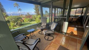 A covered outdoor area with a patio table and chairs, a view of the ocean, and a glimpse of the interior. - Paradise Found:  Spacious, Comfortable, Private Hawaiian Cottage (Lahaina)