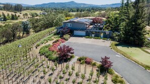 A large house with a spacious driveway, surrounded by a vineyard and a golf course. - Wine Country Retreat with Pool, Vineyard, Trampoline, Putting Green and Hot Tub (Santa Rosa)