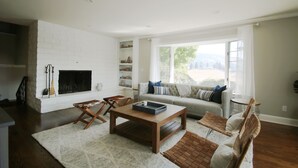 A living room with a fireplace, a sofa, a coffee table, and a dining table. - Wine Country Retreat with Pool, Vineyard, Trampoline, Putting Green and Hot Tub (Santa Rosa)