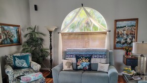 A cozy living room with a sofa, armchair, and a large window with a view of a cityscape.