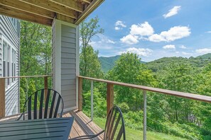 A wooden deck with two chairs and a table, overlooking a lush green landscape with mountains. - Hawks Peak 203-Mtn Condo, Entry Level, Near High Country Attractions (Seven Devils)