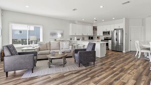 Una cocina moderna con armarios blancos, electrodomésticos de acero inoxidable y suelo de madera.