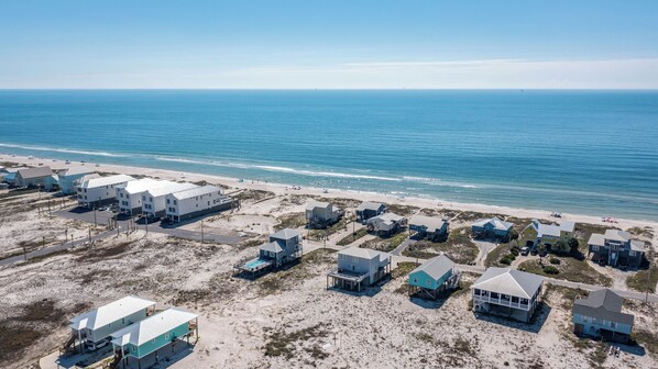 A coastal residential area with beachfront properties, including houses with balconies and a swimming pool. - Beautiful Beach House - Private Pool -Great Views -Gulf of America (Gulf Shores)