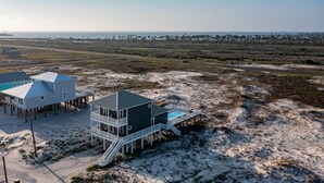 Una propiedad frente al mar con varias construcciones, incluyendo una casa principal con balcón y piscina, además de varias edificaciones más pequeñas.