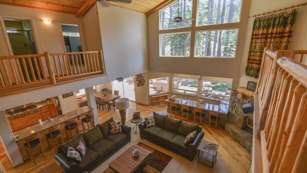 A spacious living area with a high ceiling, wooden beams, and large windows offering a view of the surrounding forest. - Kantor's Hideout: Ample TD Home with Private Hot Tub, Pool Table, Walk to Trails (Truckee)